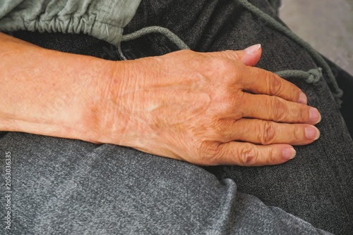 Fotografia Sitzende alte schlanke attraktive Frau mit grauer Jeanshose und grüner Bluse leg