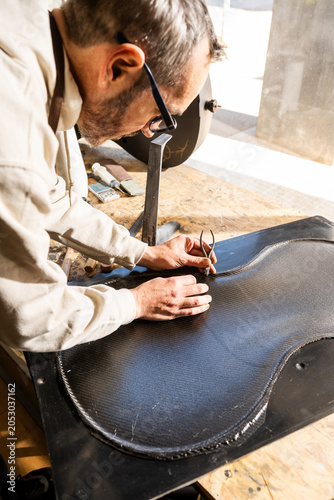 Craftsman Molds Carbon Fiber for Cello in Workshop Space With Natural Light