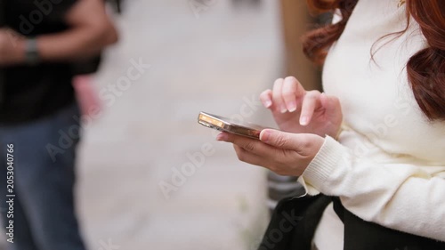 Slow motion Japanese woman uses a smartphone on a Kyoto street in daylight, creating a modern travel image for communication, technology, Japanese culture and urban lifestyle themes