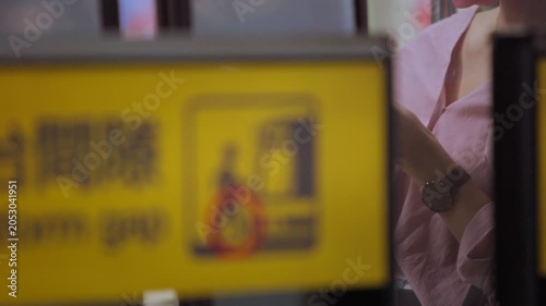 Slow motion unrecognizable Taiwanese woman uses a smartphone while metro train doors close, showing public transportation, commuting, technology and daily urban life