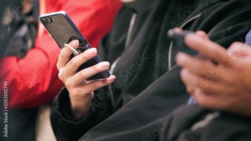 Slow motion close view of an unrecognizable metro passenger holding a smartphone, showing anonymous commuting, public transportation, communication technology and daily urban routine