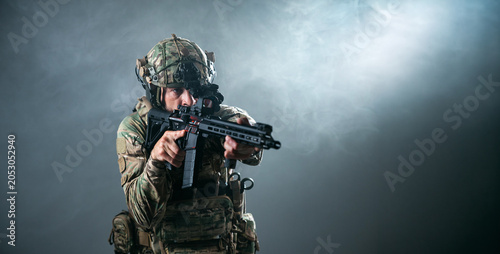 Fotografía Soldier in camouflage uniform aiming a rifle while wearing a tactical helmet and