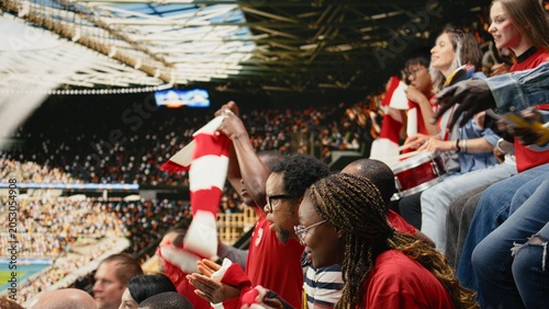 Konstfotografi Female soccer fans celebrating goal with raised arms in crowded stadium stands, red team supporters and energetic live match atmosphere in fan section, Supporters remain nervous with packed
