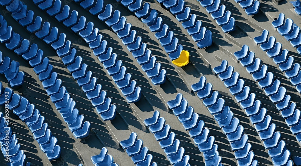 Obraz premium Many blue empty stadium seats are arranged in rows, with one yellow seat standing out
