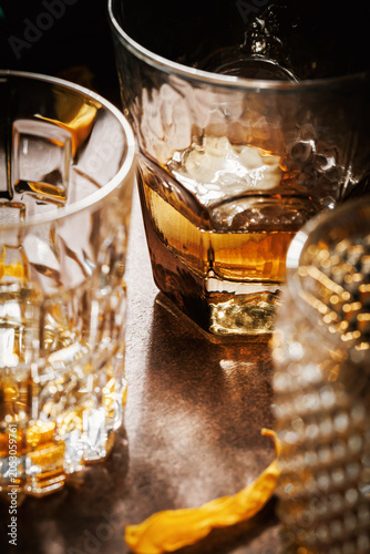 Premium whiskey still life with multiple crystal glasses, warm amber liquor reflections, shallow depth of field and elegant floral accents in a luxury bar atmosphere