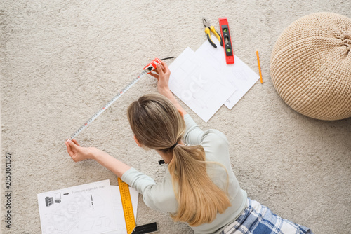 Young woman measuring floor...