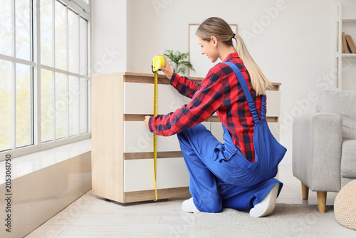 Young woman measuring furni...