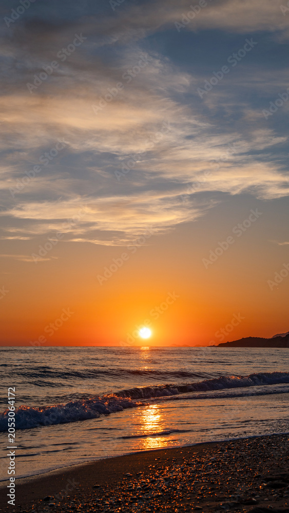 Fototapeta premium Beautiful colorful landscape with sunset on the calm sea vertical composition