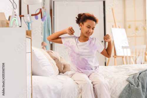 Teenage African-American girl stretching in bedroom