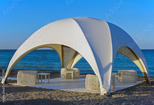A serene, high-end evening beach lounge setup featuring a large, white crossover dome tent as the centerpiece in Constanta, Romania