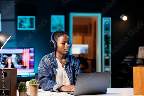 Photography Female student surfing the net and listening to music with wireless headphones and laptop, with black woman wearing headset is having a video conference on wireless computer at home office desk