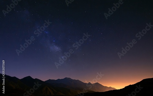 A vast night sky filled with stars and the Milky Way over silhouette mountains