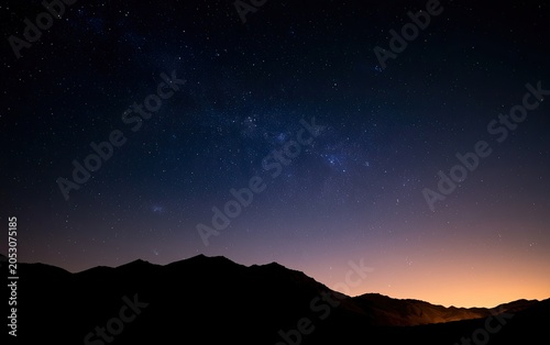 Silhouetted mountain range beneath a vast, star-filled night sky