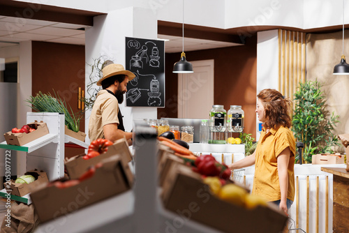 Fotografie Man and woman in zero waste store filling shopping baskets with healthy locally sourced vegetables
