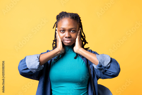 Foto African American woman troubled by excessive noise, suppressing it, bIPOC person covering ears with hands, annoyed by loud surrounding sounds, isolated over studio background