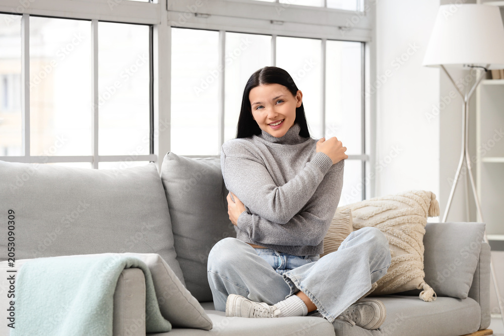 Obraz premium Beautiful young woman hugging herself on sofa at home