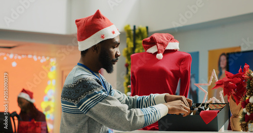 Quadro su tela Manager wearing Santa hat arranging formal attire neckties in Christmas decorate