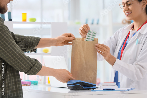 фотографія Pharmacist handing prescription medication to customer in pharmacy, healthcare a
