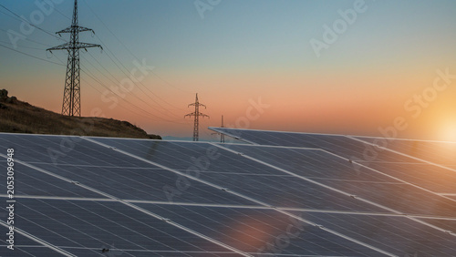 Fotografia Solar panels at sunset generating clean renewable energy with power transmission