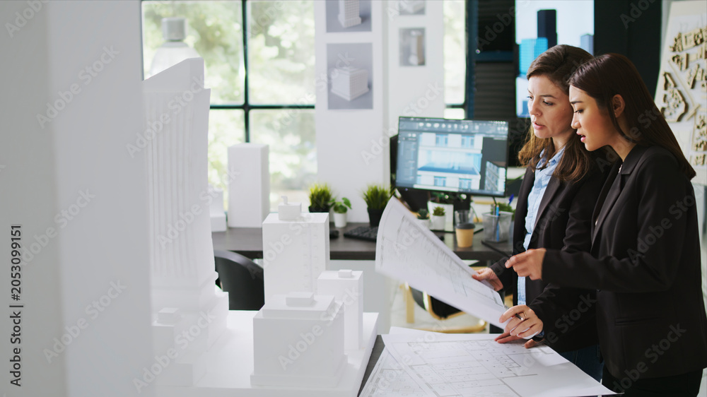 Fototapeta premium Architects team studying 3D printed building model in office, looking at scale and outline to reveal floor plan measurements, creative agency employees working with architectural blueprints