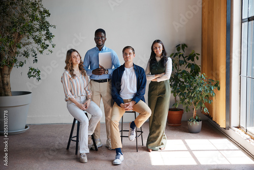 Fotografie Four smiling young diverse professionals are posing for a portrait in a bright c