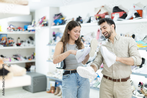 Foto Male partner brings interesting sneakers models to girl, helps in selection of s