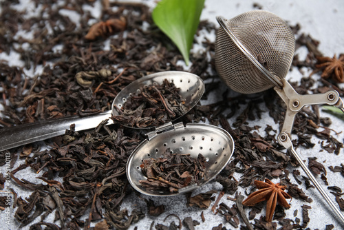 Konstfotografi Infuser spoon with dry black tea leaves and star anise on grey background, close