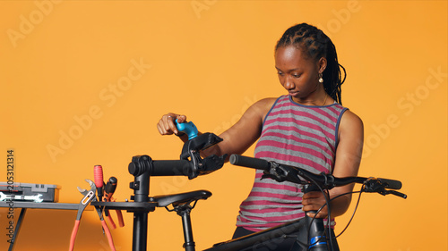 Canvas Print Cheerful worker setting up bike repair stand before servicing malfunctioning wheels, studio background, with happy repairman securing bicycle on workstand before patching up components