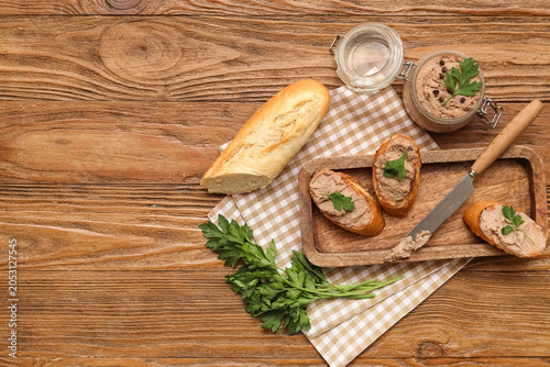 Jar of tasty pate with toasts, parsley and knife on wooden background