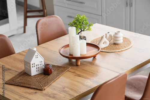 Foto Wooden dining table with houseplant and candles in interior of kitchen, closeup