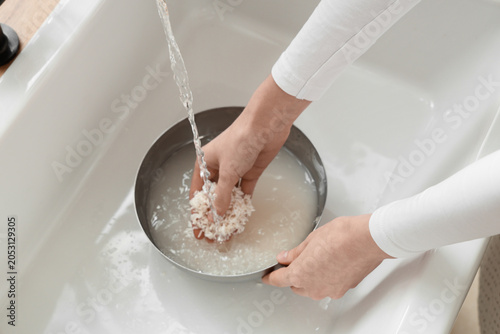 Konstfotografi Woman rinsing rice in bowl under running water, closeup