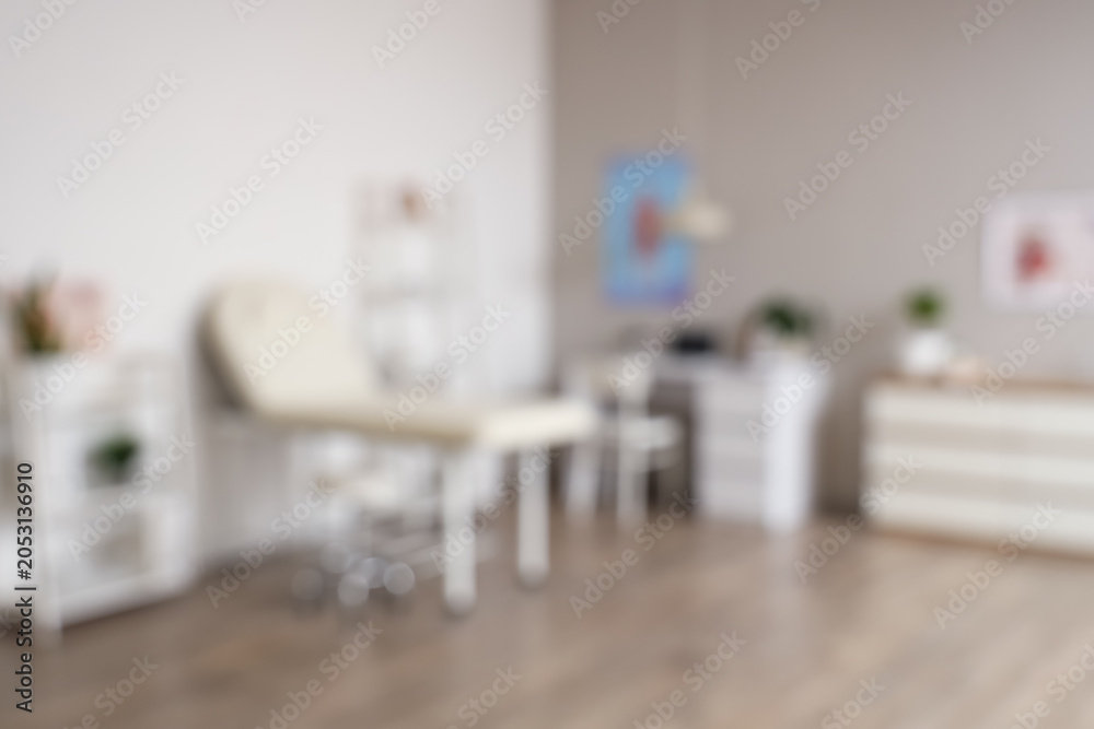Fototapeta premium Blurred view of medical office with couch, shelf units and doctor's workplace