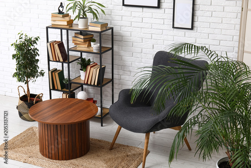 Interior of modern living room with armchair and bookshelf near white brick wall
