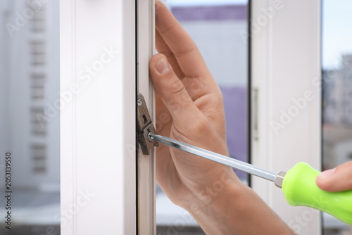 Photos Worker with screwdriver installing window indoors, closeup