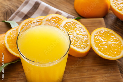 Obraz na plátně Freshly squeezed orange juice in glass with sliced oranges on wooden table, heal