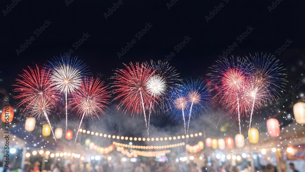 Obraz premium Fireworks illuminate the night sky above a festive outdoor market area decorated with glowing paper lanterns during a vibrant summer evening celebration.