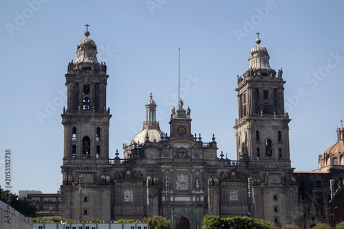 Front view of the Metropolitan Cathedral in Mexico City, featuring its iconic twin bell towers in a clear blue sky