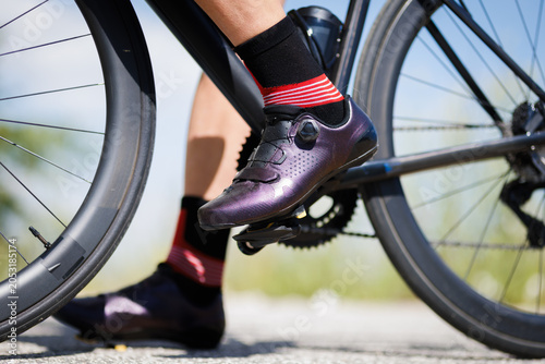 Person wearing cycling shoes and socks while riding a road bike in an outdoor setting during a sunny day