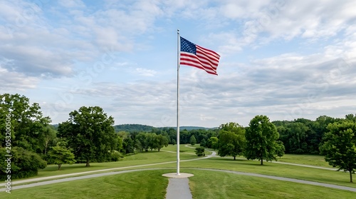 American flag waving on a tall pole in a green park setting