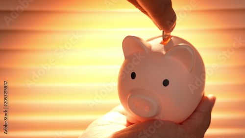 Foto An office worker deposits a coin into a piggy bank under warm sunlight, symbolizing financial responsibility, saving for the future, discipline, security, and the value of steady, mindful planning