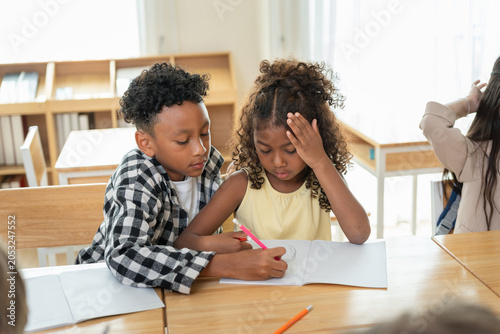 Quadro su tela Kind boy helping classmate with homework in modern elementary classroom, Support