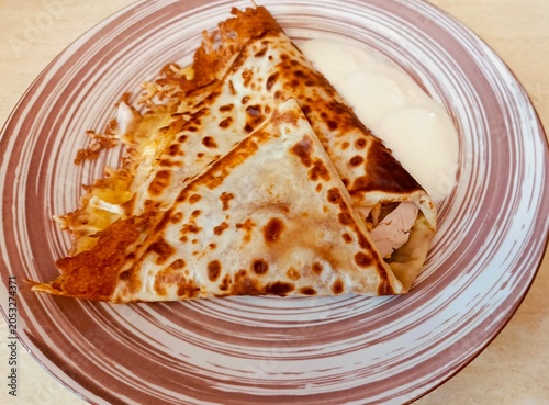 Fried Crepes with Meat Filling and Sour Cream on a Striped Plate – Top View