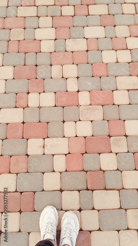 Top View of Feet in White Sneakers on Colorful Geometric Paving Stones - POV Lifestyle Shot