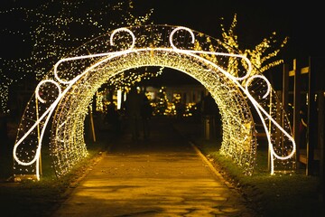 Warm yellow Christmas fairy lights icicles hanging from a wooden fence or cottage roof structure at night.
