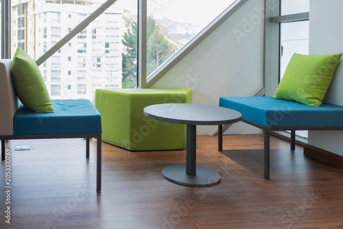 Tableau sur toile Three modern, minimalist seats in vibrant colors like phosphorescent green and blue, in a space surrounded by windows