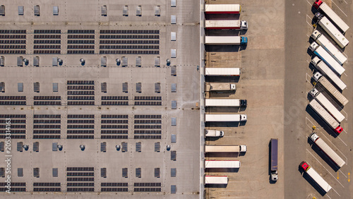 Aerial View of Logistics Warehouse with Solar Panels and Loading Dock Trucks