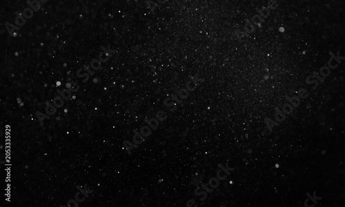 Floating dust particles illuminated against a dark background during a soft light presentation