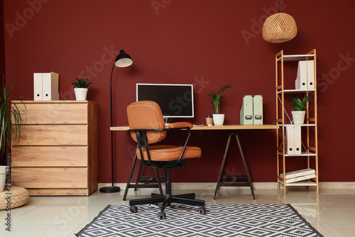 Foto Modern home office interior with computer monitor, brown leather chair, wooden d