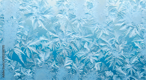 Intricate ice crystal patterns form beautiful natural geometric designs on a cold glass window pane during a freezing winter day