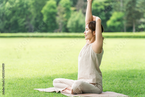 Women doing yoga, Pilates, forest bathing, gymnastics, stretching, and exercise in the park.